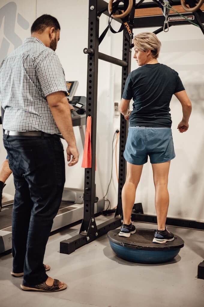 An exercise therapist demonstrating the use of a balancing ball to a participant in a disability rehabilitation centre