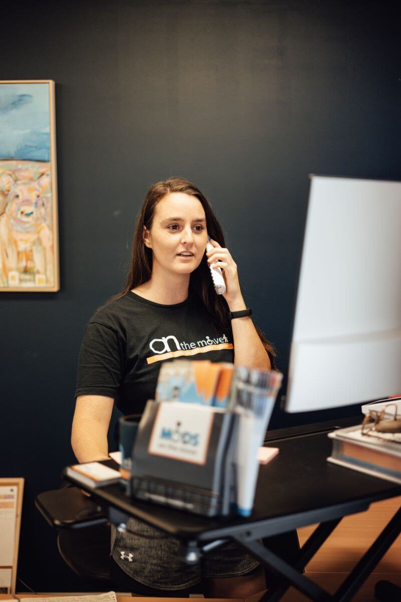 A woman talking on the phone while sitting at a desk.