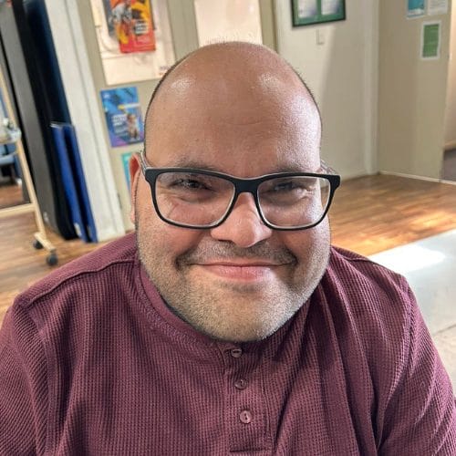 A bald man with glasses smiling in a disability rehabilitation centre.