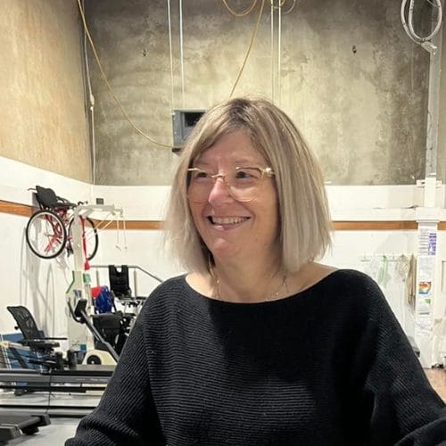 A woman smiling in front of a bike in a disability rehabilitation centre.