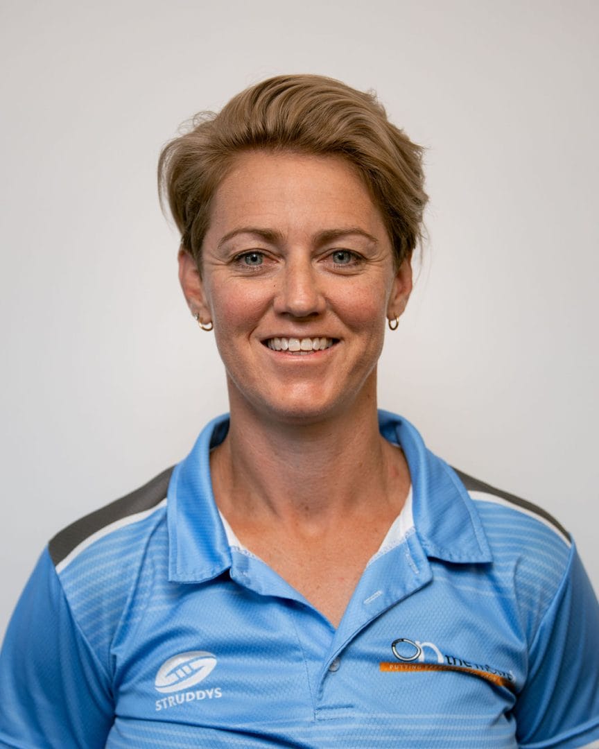 A woman in a blue polo shirt smiling.